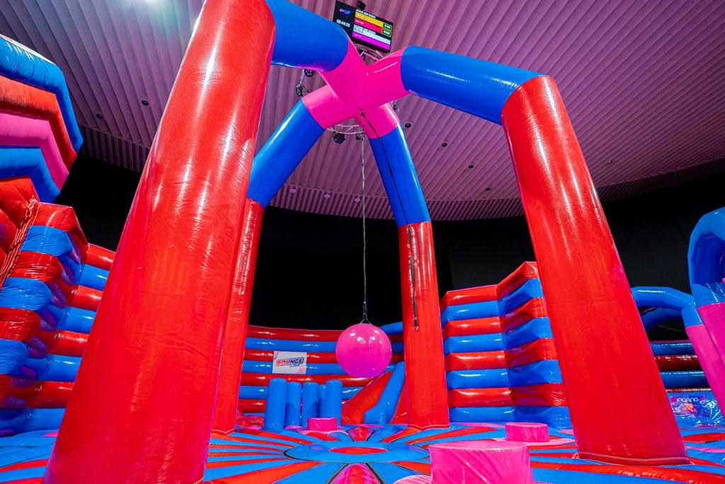 Swing Him Off obstacle in inflatable park – red and blue inflatable game with a large swinging ball to knock off opponents