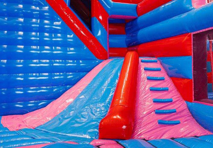 Volcano Slide obstacle in inflatable park – blue and pink inflatable climbing and slide feature with steps and slide surface