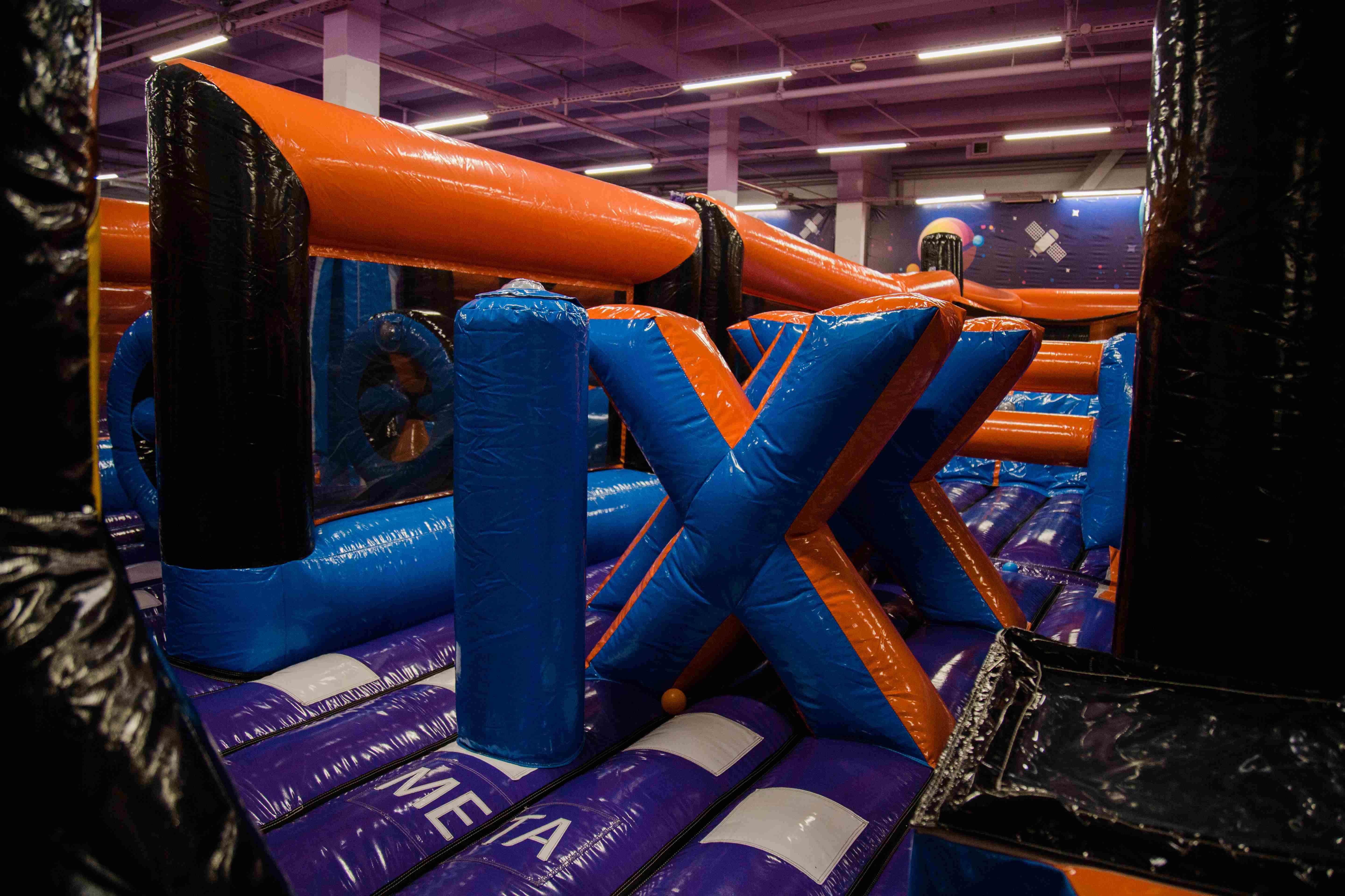 X obstacle in indoor inflatable park – blue and orange inflatable challenge for climbing and dodging