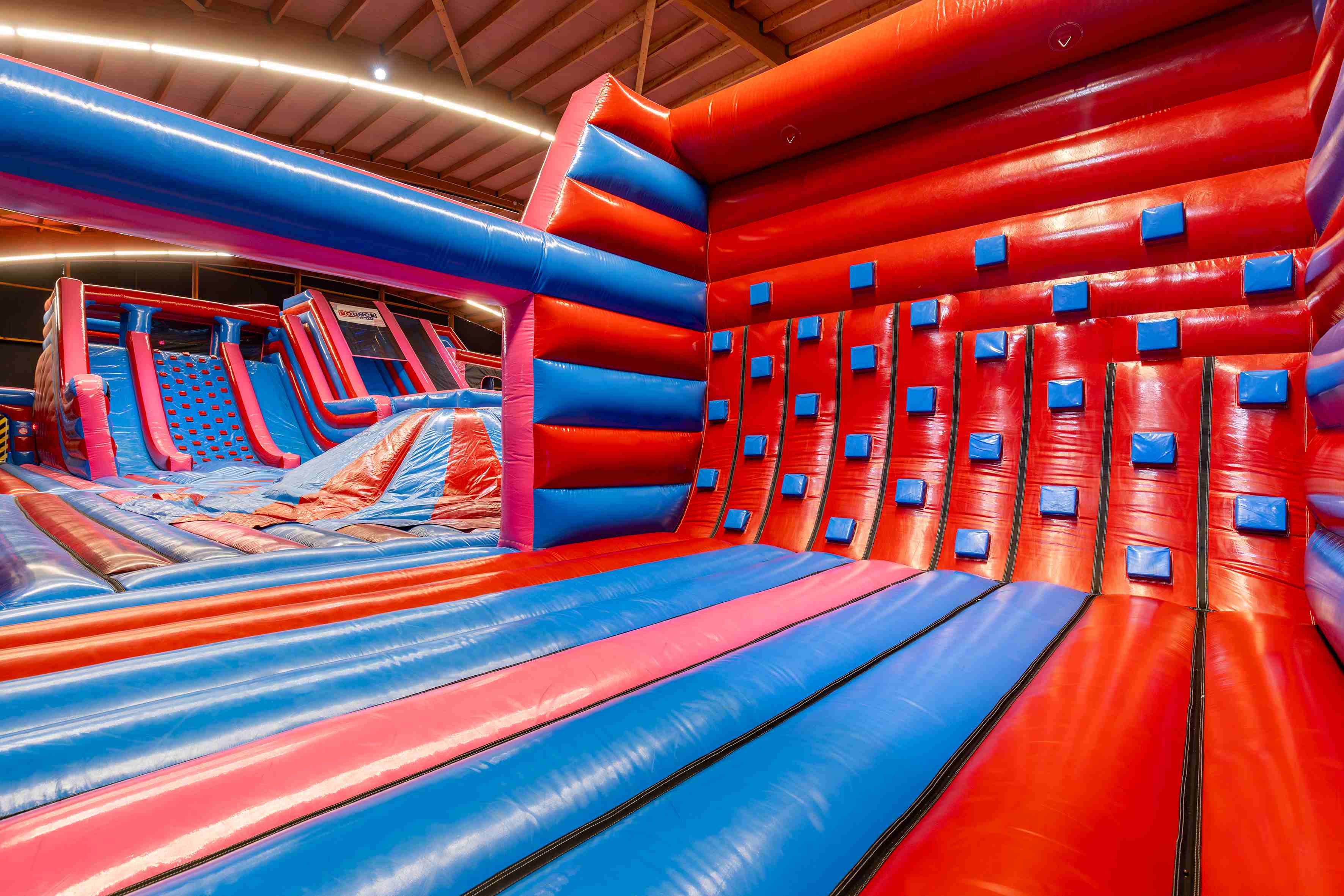 Climb Wall obstacle in inflatable park – red and blue inflatable climbing wall with hand and foot grips