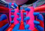 Inflatable obstacle with vertical pillars and blue push arms in a colourful inflatable park