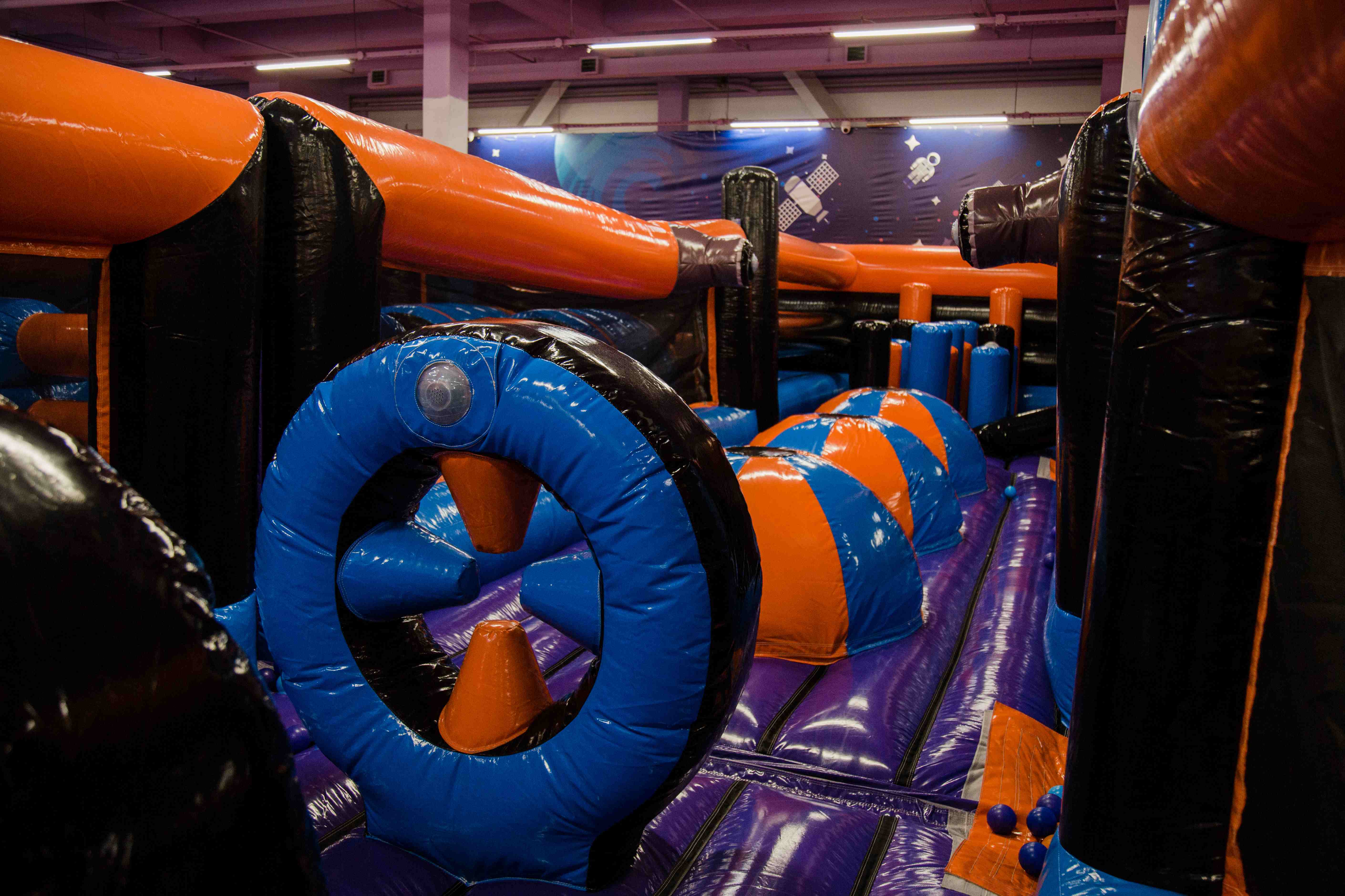 Inflatable park obstacle with inflatable rings and crawl tunnel – blue, orange, and black design