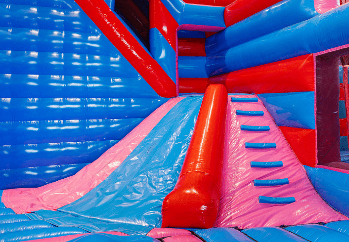 Obstáculo Volcano Slide en parque hinchable – tobogán hinchable azul y rosa con escalera y superficie de deslizamiento