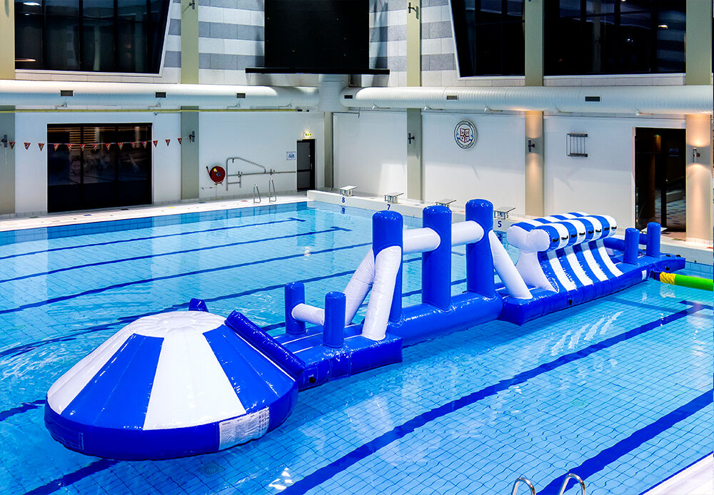 Unique inflatable adventure run blue/white 16m swimming pool with challenging obstacle objects and round slide for both young and old. Buy inflatable water attractions online now at JB Inflatables UK